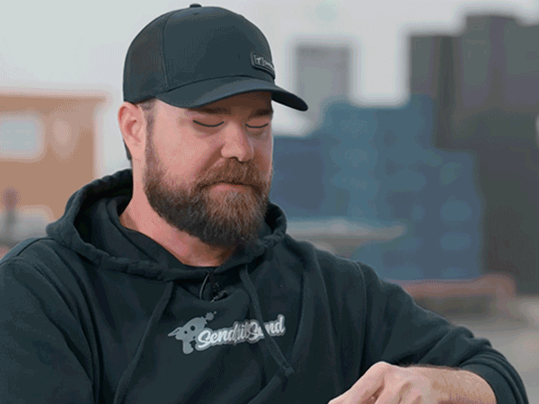 A close-up photograph of a precision laser cutting head emitting a bright blue beam as it cuts through a metal sheet, surrounded by orange sparks.